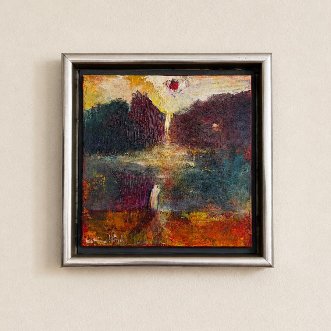 A square framed abstract painting with a textured impasto style, featuring a dark landscape with a bright sun-like circle near the top center. The painting is housed in a silver-toned frame and mounted on a light beige textured wall.